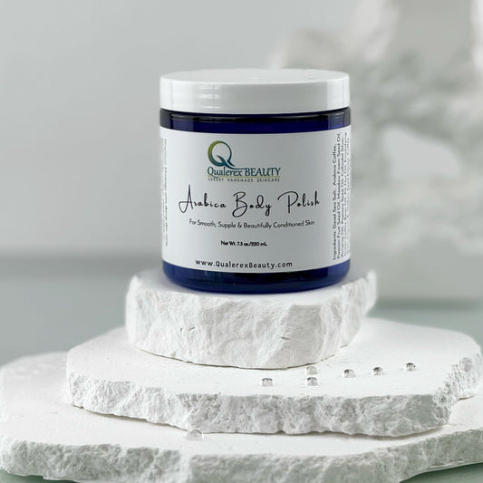 A jar of Qualerex Beauty Arabica Nourishing Body Polish on a stack of white stones