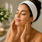 A woman wearing a towel on her head is washing her face after using the Chlorella Spirulina Clay Mask in a bathroom.